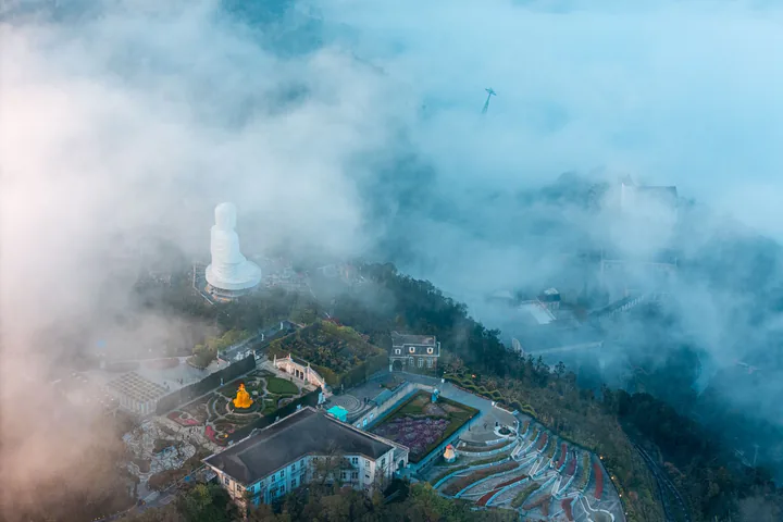 Tượng Phật và sườn núi Bà Nà Hills nhìn từ trên cao giữa mây
