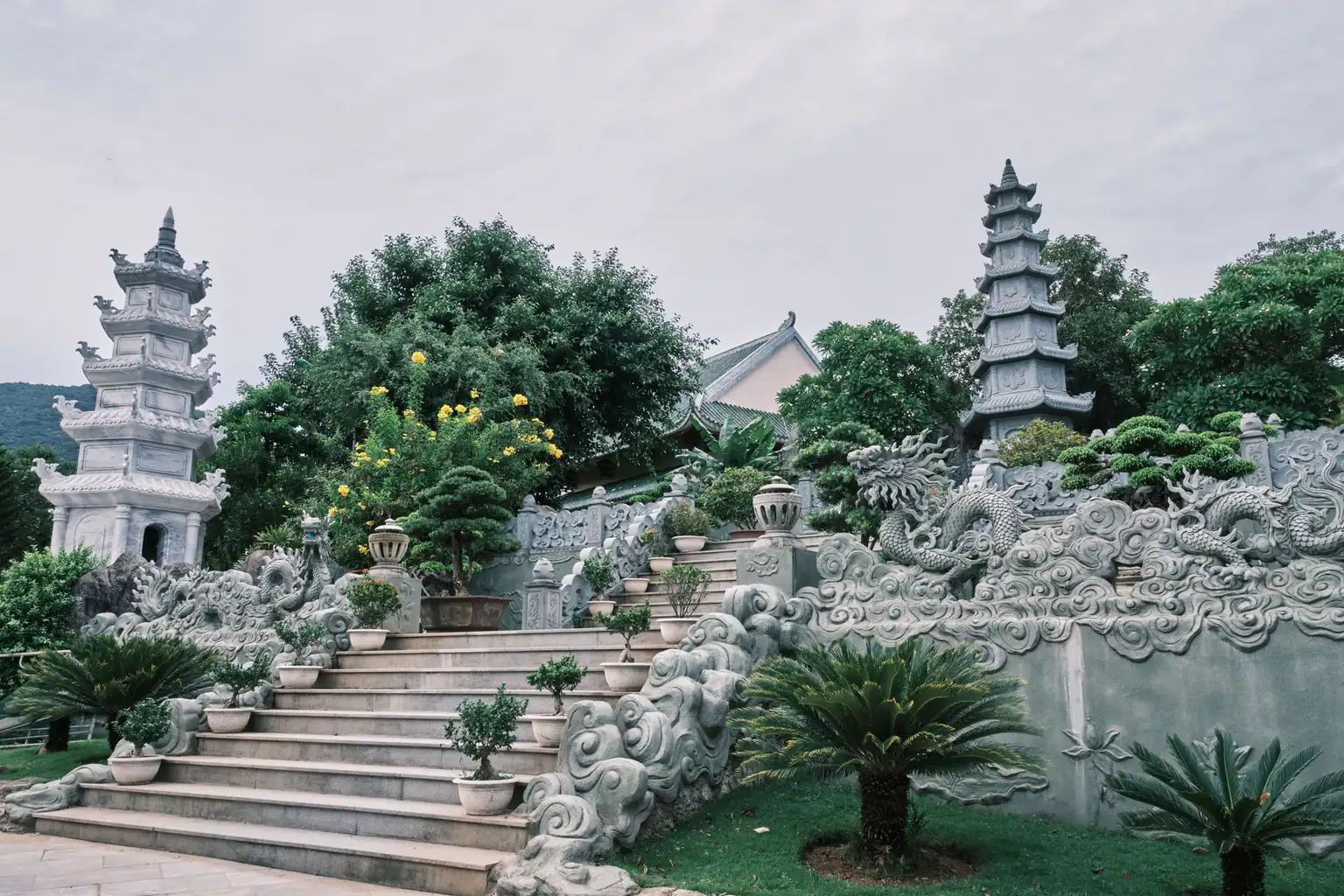 Stone steps carved with dragons leading to a temple garden with two pagodas