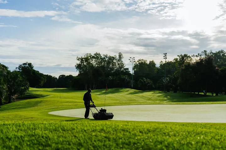 Người vận hành máy chăm sóc thảm cỏ trên sân golf rộng