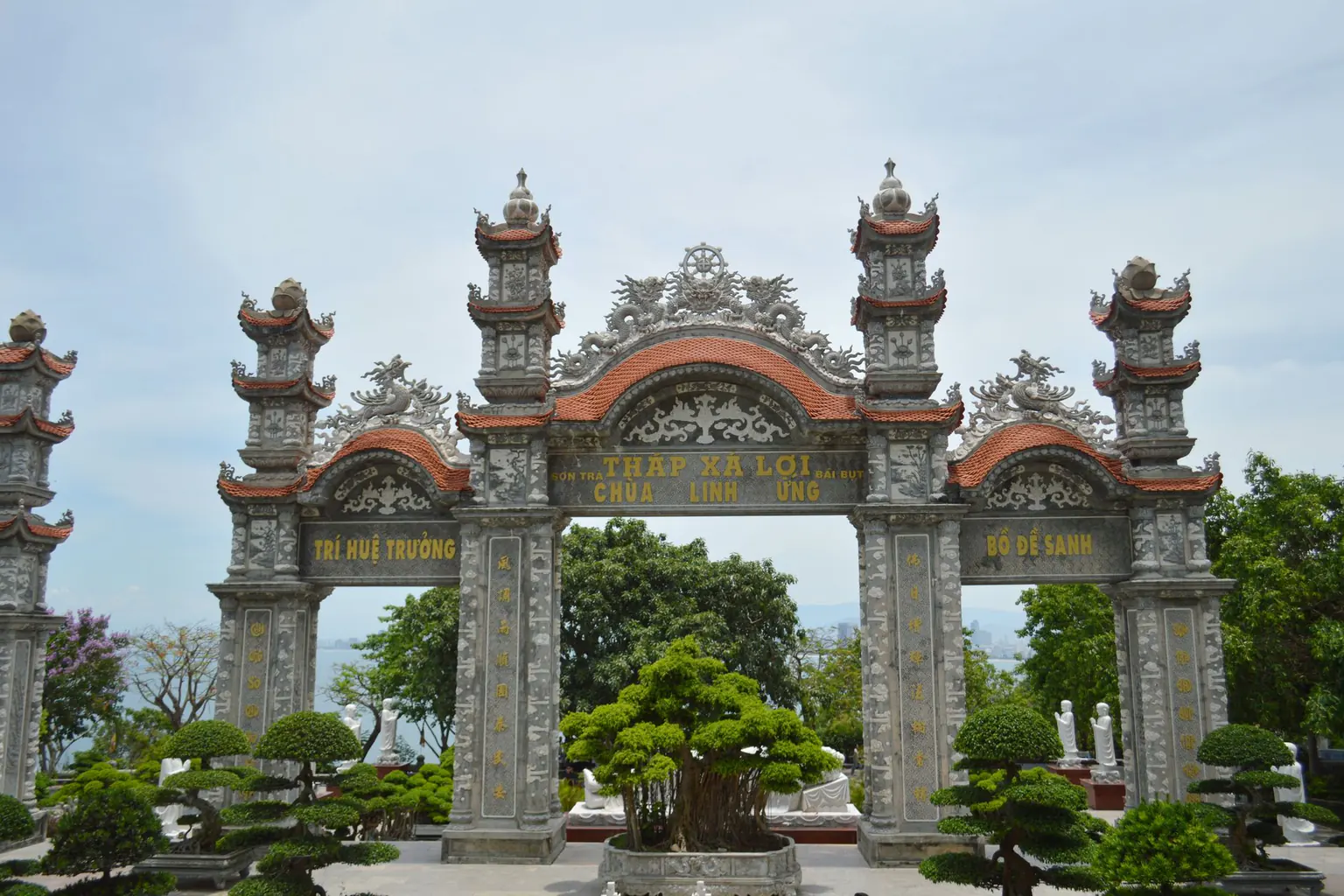 Carved stone gate and bonsai trees at Linh Ung Pagoda
