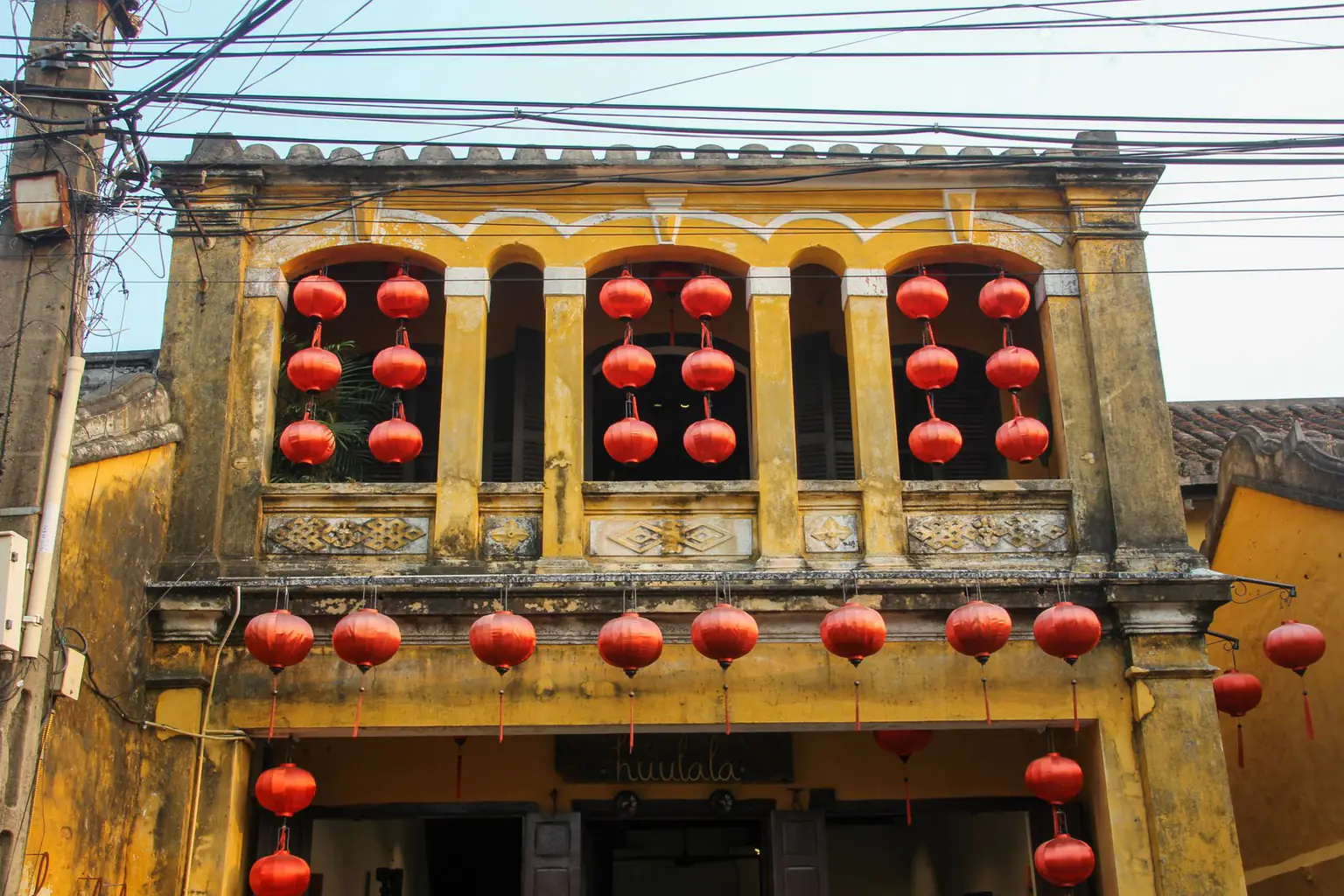Yellow old-town facade hung with red lanterns in Hoi An