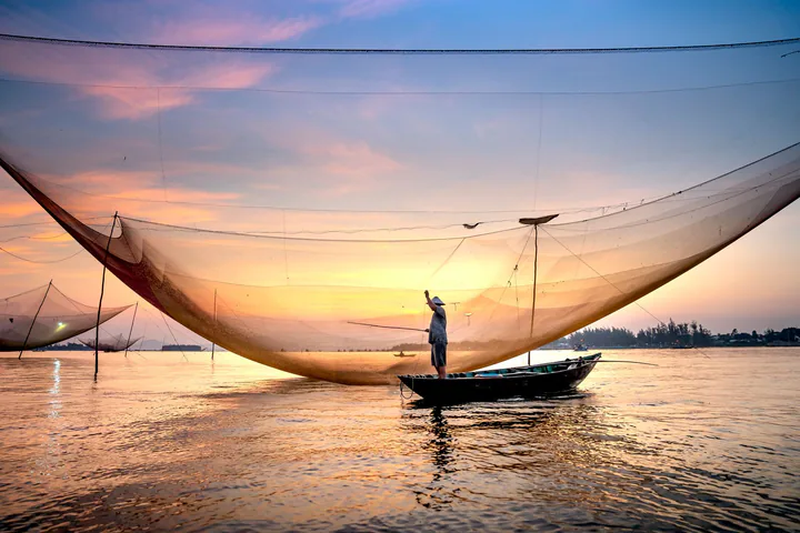 Ngư dân thả lưới trên mặt nước Hội An trong ánh hoàng hôn