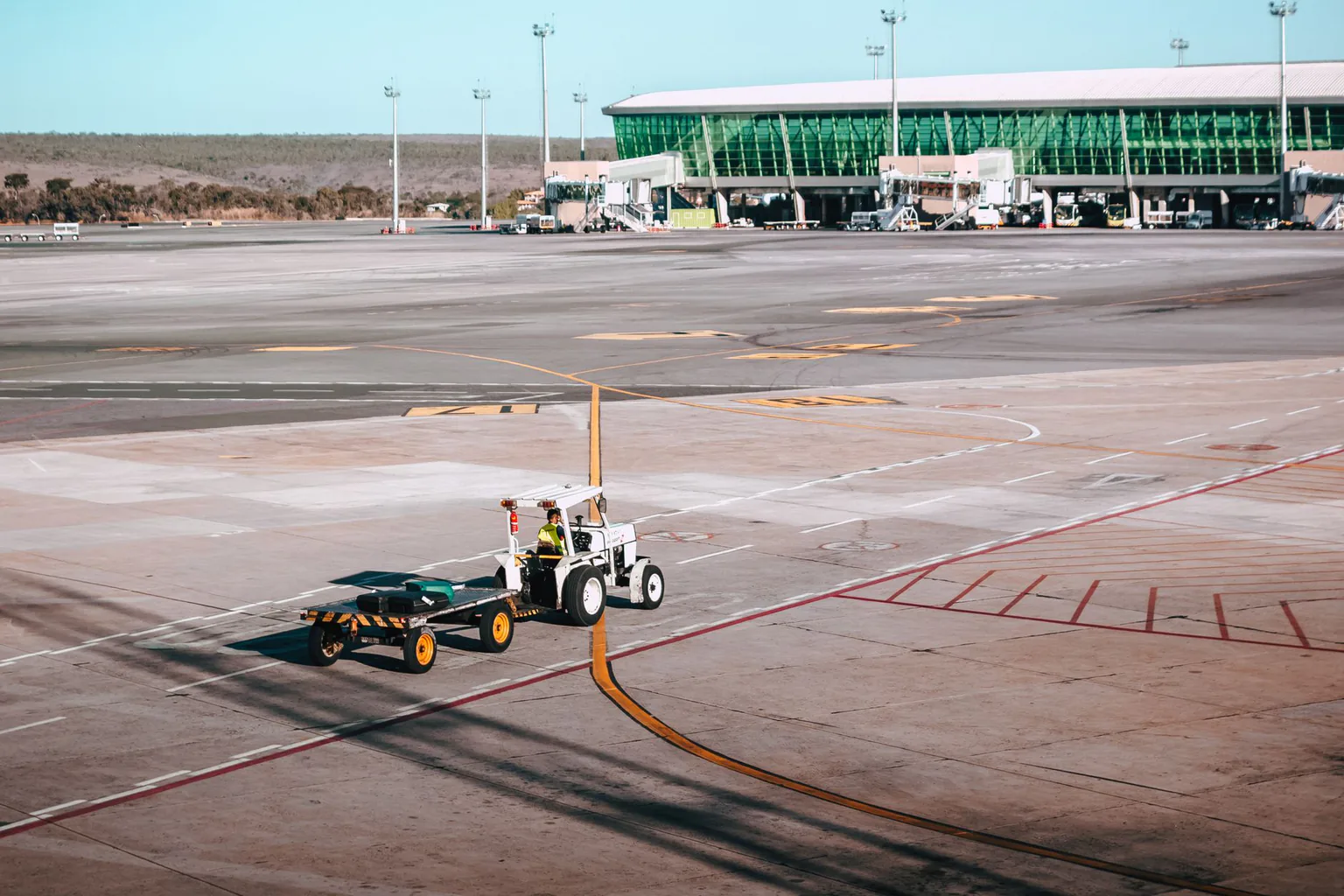 Luggage cart on the apron next to a modern airport terminal
