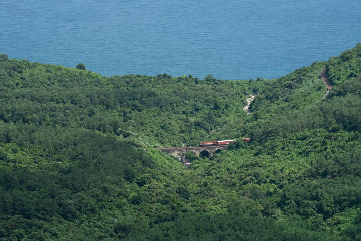 A train crossing a bridge through coastal forest