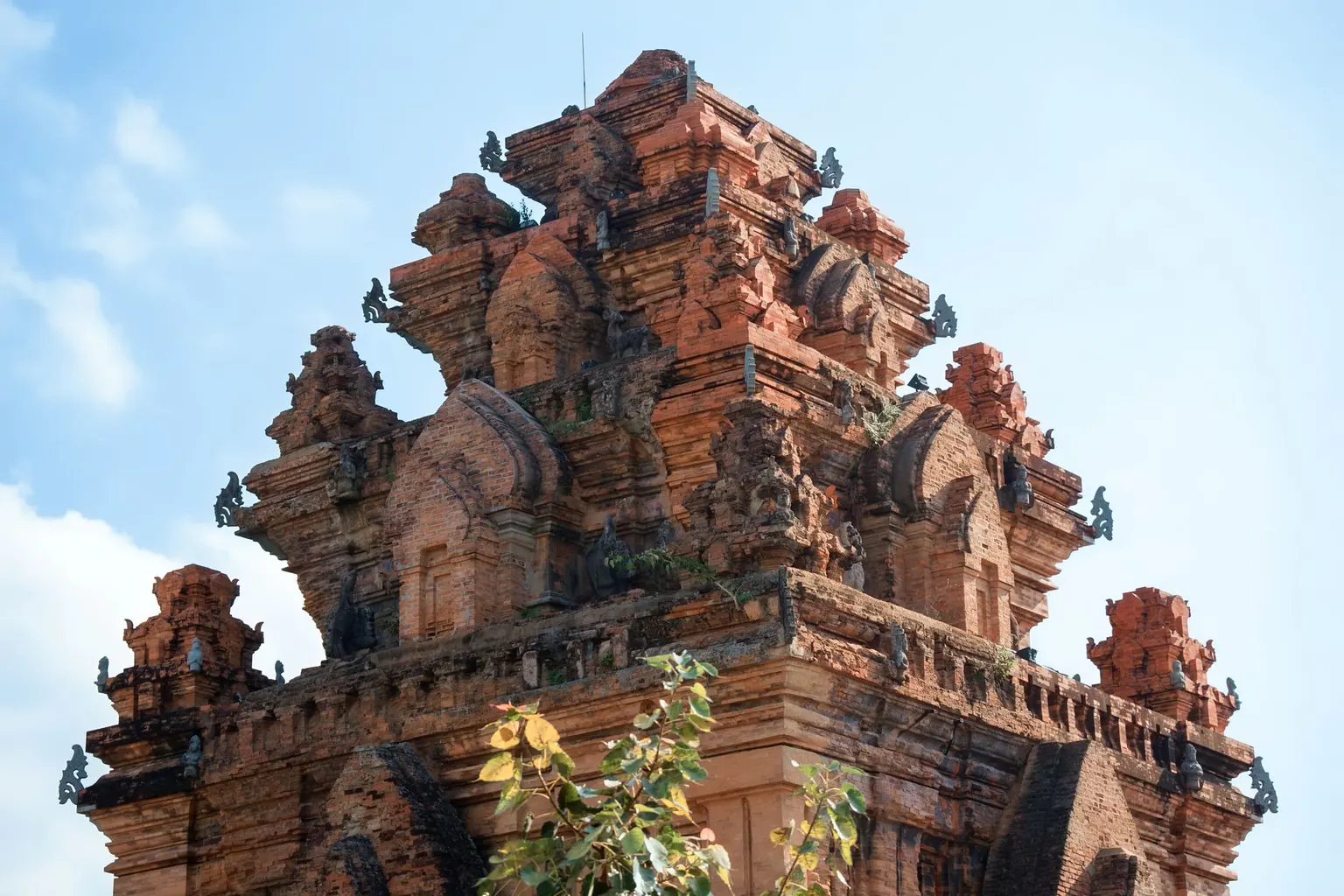 Close view of a carved red-brick Cham tower under a blue sky