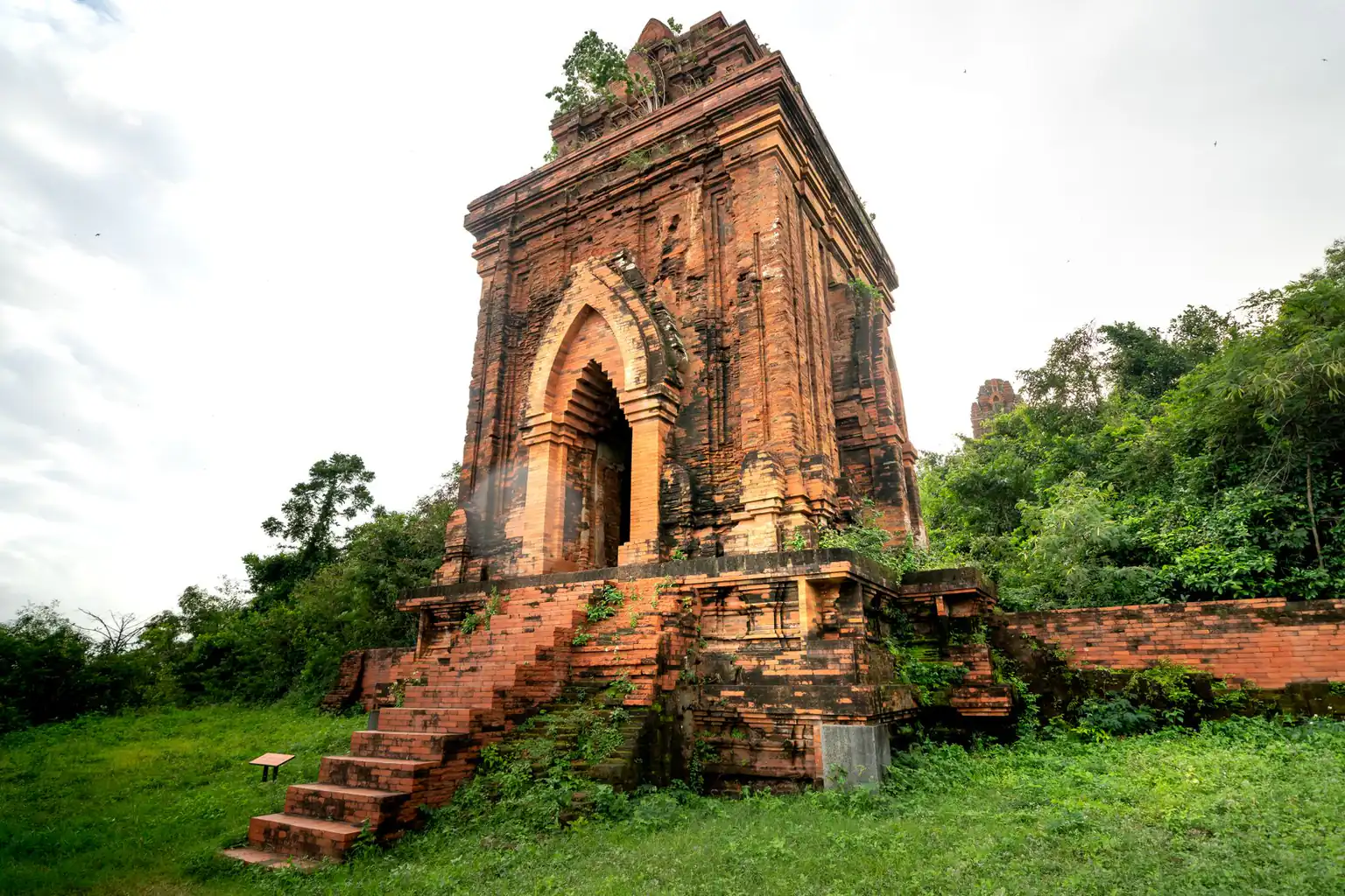 A red-brick tower with stone steps on a green lawn