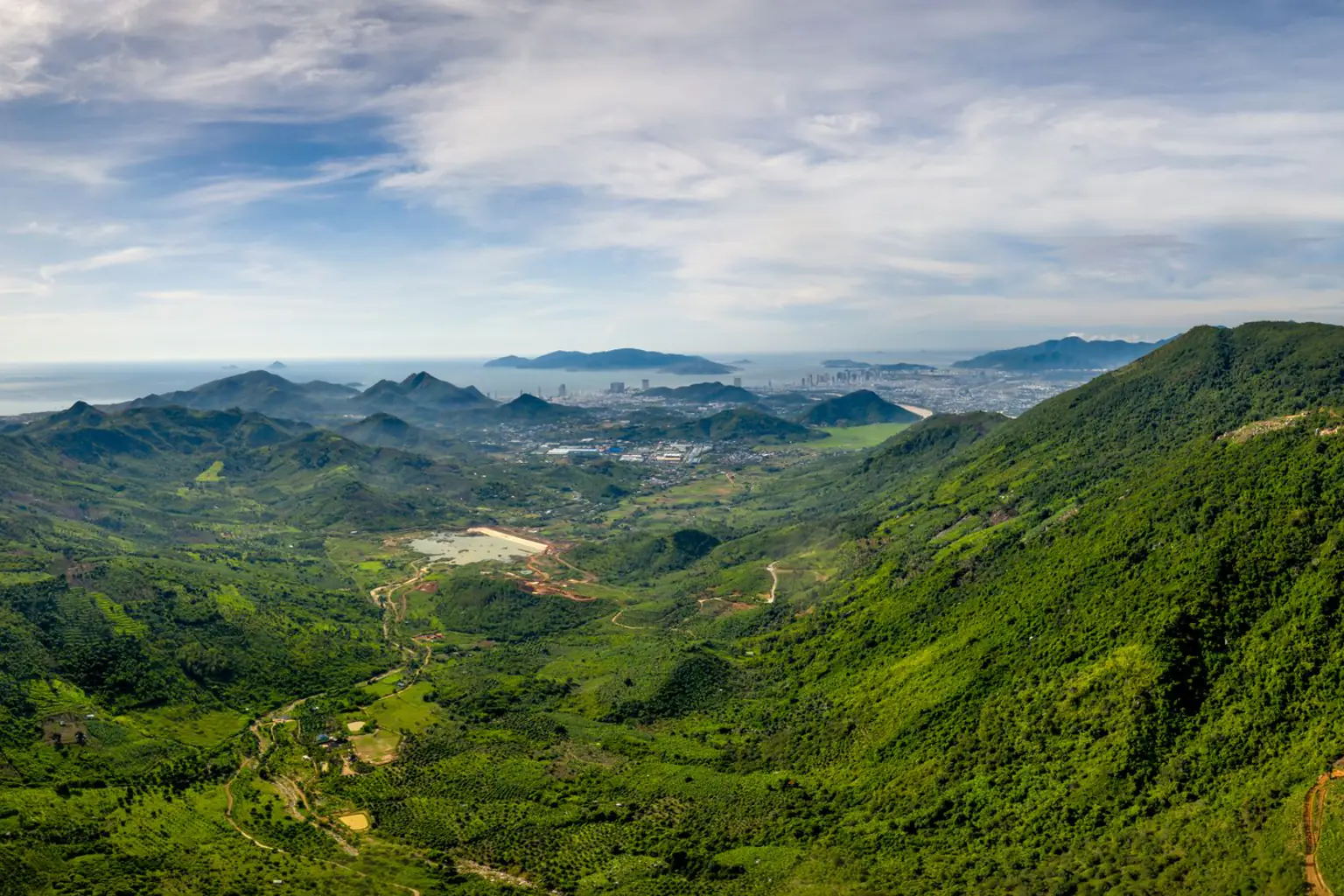 Aerial panorama of green mountain valleys opening toward the coast