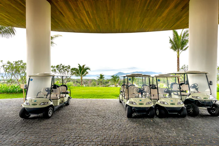 Những chiếc xe golf đỗ dưới mái đón nhìn ra sân cỏ xanh